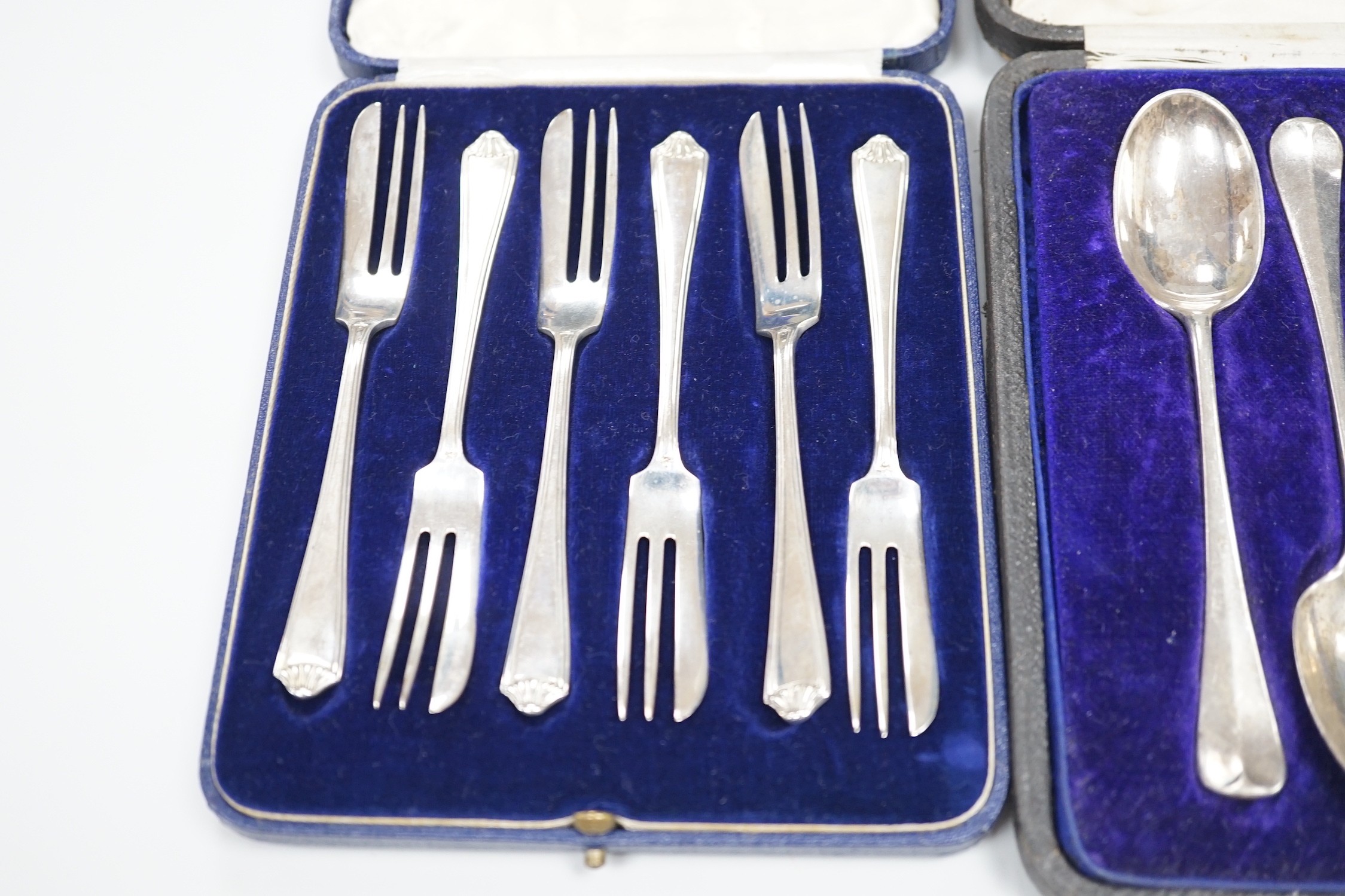 A cased set of twelve George V silver rat-tail pattern teaspoons, William Hutton & Sons, Sheffield, 1915 and a similar cased set of six pastry forks by Mappin & Webb, 13.1oz.